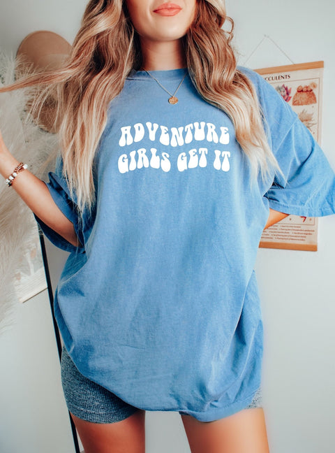 Woman wearing an oversized "Adventure Girls Get It" t-shirt, perfect for your girls trip gifts, best friend shirts, or just the right oversized tee for your summer vibes, road trip aesthetic!