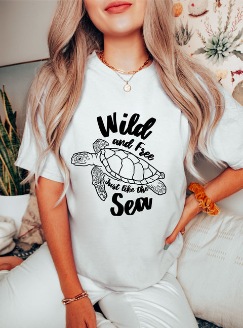 Woman wearing an oversized Trendy Sea Turtle T-shirt with the cutest quote, "Wild and Free, just like the Sea" for the ocean lovers & salty girls.