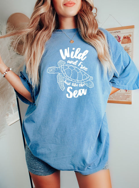 Woman wearing an oversized Trendy Sea Turtle T-shirt with the cutest quote, "Wild and Free, just like the Sea" for the ocean lovers & salty girls.
