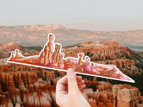 10" long extra large vinyl sticker that portrays a rocky scene from Bryce Canyon Utah in beautiful orange, pink, and red tones.  Waterproof, scratch and weather-resistant, you can put these stickers on all of your outdoor gear like your favorite tumbler or water bottle, no matter what the size!