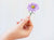 image shows someone holding a small purple aster flower sticker