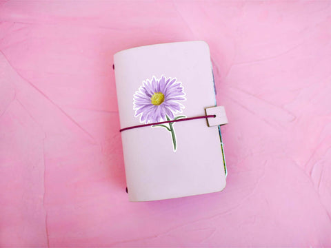 image shows a pink journal with a purple aster flower sticker on the journal cover.