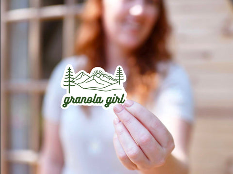 Vinyl sticker showing an image of a mountain scene and the text "granola girl" for your coffee mug, water bottle, laptop, car sticker, journal, window, or other smooth surface.